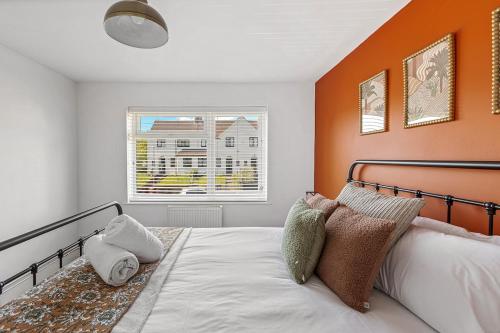 a bedroom with a bed with an orange wall at Modern 2-Bed House in Reading in Reading