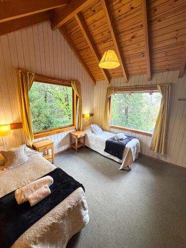a bedroom with two beds and two windows at Apart Hotel del Pellin in San Martín de los Andes