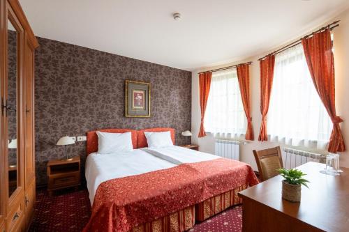 ein Schlafzimmer mit Bett, Schreibtisch und Fenstern in der Unterkunft Hotel Hadjiite in Kopriwschtiza