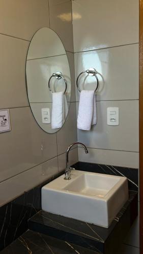 a bathroom with a sink and a mirror and towels at Cardoso Palace Hotel Rio Verde in Rio Verde