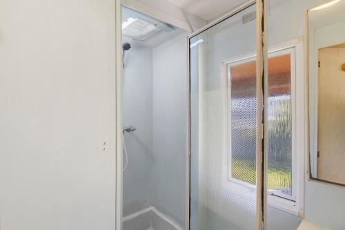 a glass shower in a bathroom with a window at Mobilehome chez dede in Porto-Vecchio