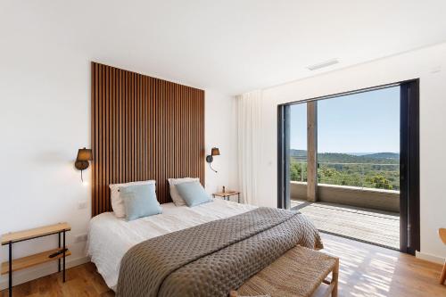 a bedroom with a large bed and a large window at Villa Schena Villata in Zonza