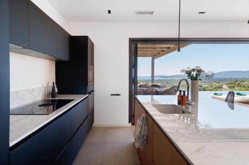 a kitchen with a sink and a large window at Villa Schena Villata in Zonza