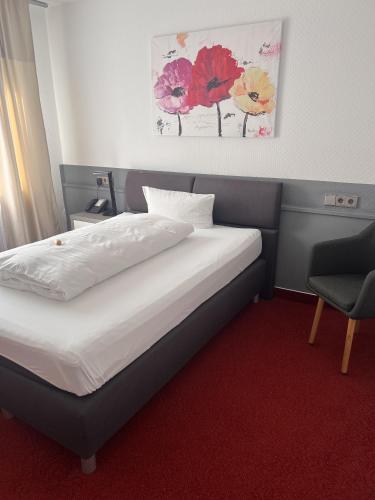 a bedroom with a bed and a chair in it at Parkhotel Krone Maleck in Emmendingen