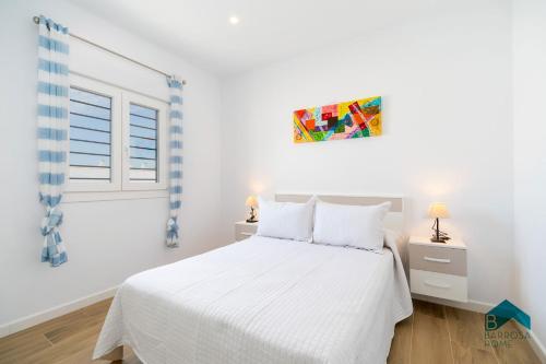 a white bedroom with a white bed and a window at Ginebra A BARROSAHOME in Novo Sancti Petri