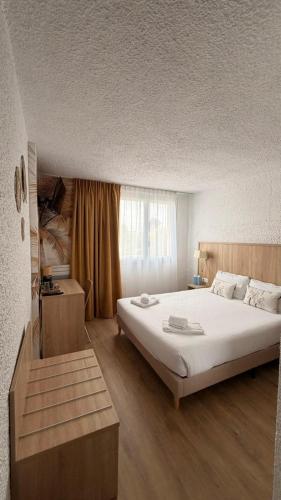 a bedroom with a large white bed and a window at Cit'Hôtel Le Quai 9 in Challans