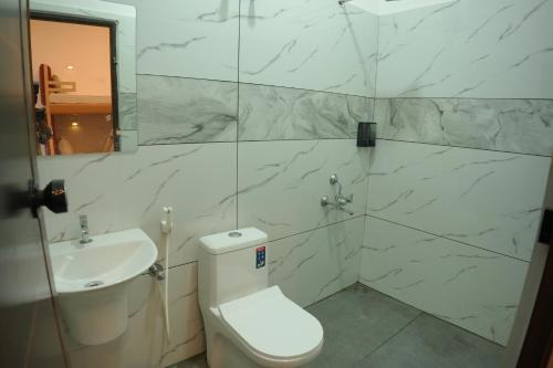 a white bathroom with a toilet and a sink at Dune Hostel - Dune Homestay in Alleppey