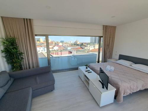 a bedroom with a bed and a couch and a tv at Figueira Beach Apartment in Buarcos