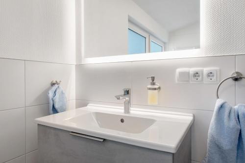 a white bathroom with a sink and a mirror at Seetraum Berger in Hagnau