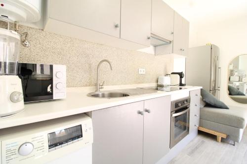 a kitchen with white cabinets and a sink at Little Paradise in Castro Marim