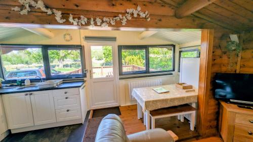 a kitchen with white cabinets and a table and windows at Lunalodge in Trawsfynydd