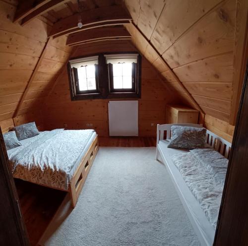 an attic bedroom with two beds and a window at Zrub u Zuzany in Lazy pod Makytou