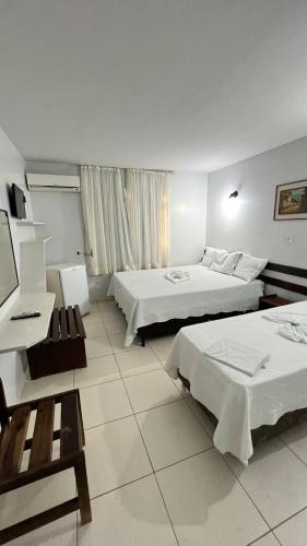a hotel room with two beds and a desk at Cardoso Palace Hotel Rio Verde in Rio Verde