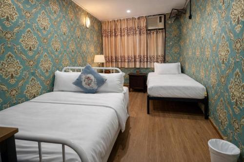 two beds in a room with blue and gold wallpaper at Reliance Block C 12f in Hong Kong