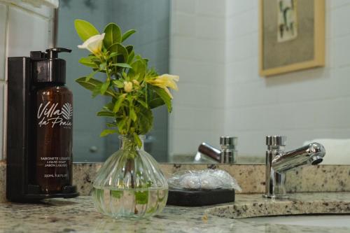 a vase with flowers in it on a bathroom counter at Samba Villa da Praia in Salvador