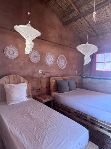 a bedroom with two beds and two chandeliers at Mbin Maak du Saloum in Mar Lodj
