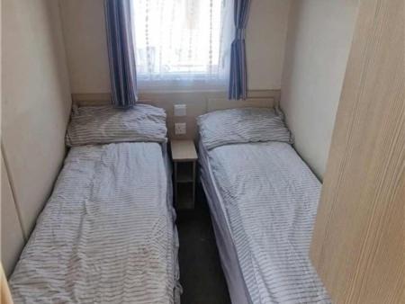 two beds in a small room with a window at Abi tebay oakfields towyn in Kinmel Bay