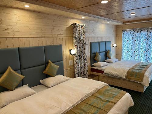 a bedroom with two beds in a room with wooden walls at Kashmir cottage in Pahalgām