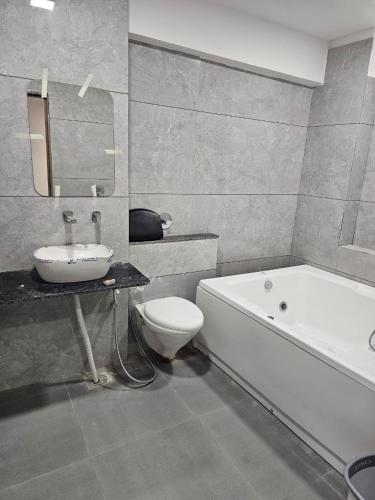 a bathroom with a tub and a toilet and a sink at Hotel Royal Heritage in Gandhinagar