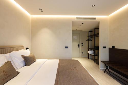 a bedroom with a large white bed and a television at Safin Hotel & Spa in Vlorë