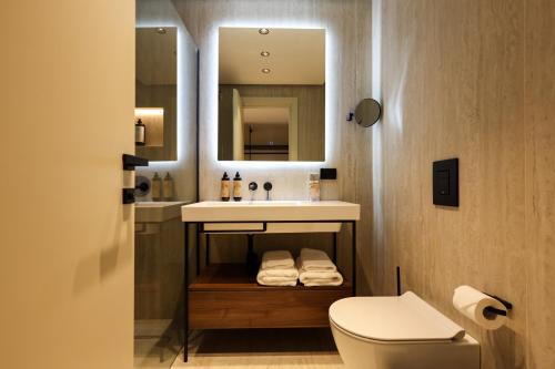 a bathroom with a sink and a toilet and a mirror at Safin Hotel & Spa in Vlorë