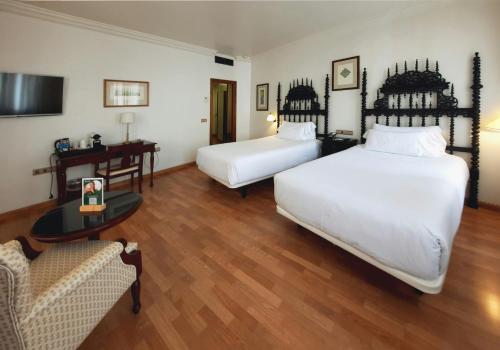 a hotel room with two beds and a couch at Sercotel Palacio de los Gamboa in Granada