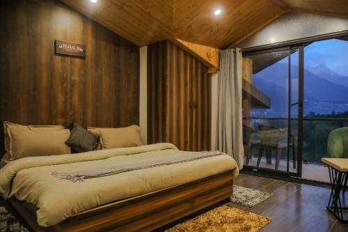 a bedroom with a bed in a room with a balcony at HOGS Panorama - Manali in Manāli