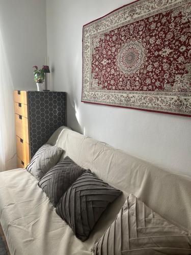 a bed with pillows and a rug on a wall at Petit cocon à 10 min de Paris in Cachan