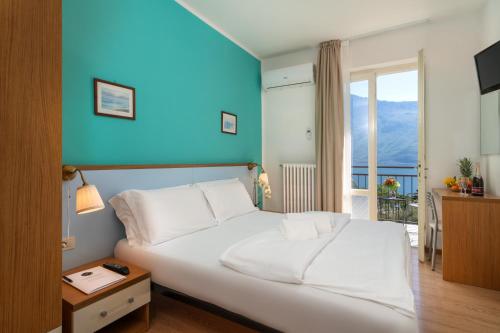 a bedroom with a white bed with a blue wall at Hotel Silvana Garnì in Limone sul Garda