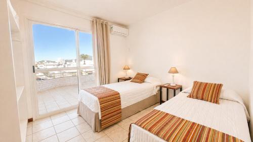 a bedroom with two beds and a balcony at Ingleses Holiday Studios in Florianópolis