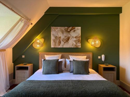a bedroom with a large bed with green walls at Hôtel Deybach in Munster