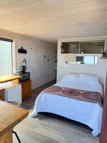 a bedroom with a bed and a desk and a table at Tinaja en la playa para 2 in Matanzas