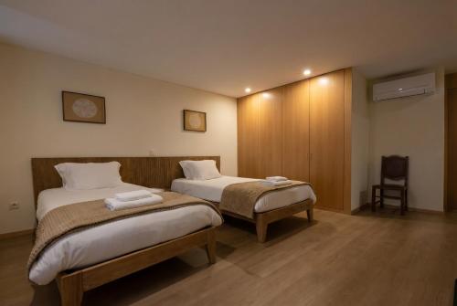 a hotel room with two beds and a chair at BUTEKO HOUSE AL in Miranda do Douro