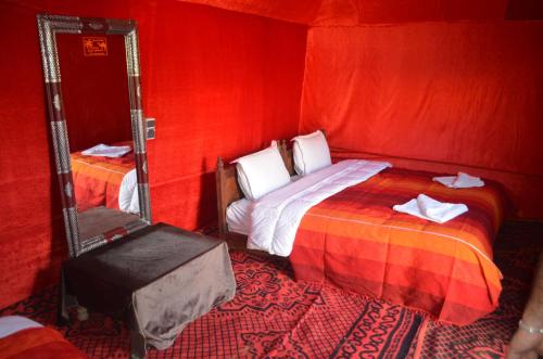 a red room with a bed and a mirror at La Source Desert Camp in Adrouine