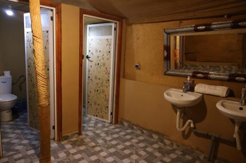 a bathroom with two sinks and a door with a mirror at La Source Desert Camp in Adrouine