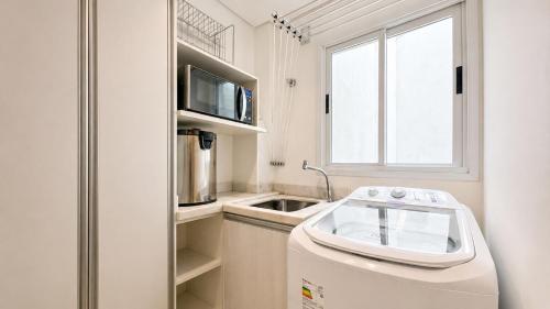 a small kitchen with a refrigerator and a window at Ingleses Holiday Studios in Florianópolis