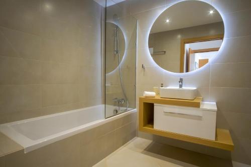 a bathroom with a sink and a mirror and a tub at Rooftop pool & Luxury apartment in Lagos