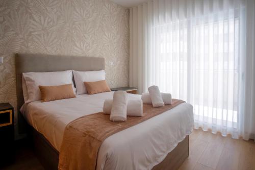 a bedroom with a large bed with white sheets and a window at Rooftop pool & Luxury apartment in Lagos