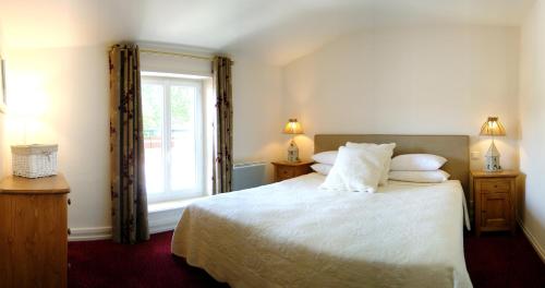 a bedroom with a bed with white sheets and a window at La Rose in Juliénas