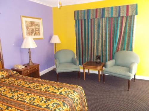 Una habitación de hotel con una cama y dos sillas. en Hillside Motel, en Homer