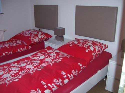 a bedroom with two beds with red covers at Ferienwohnung Störkle in Maselheim