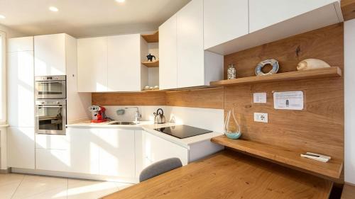 a kitchen with white cabinets and wooden walls at Marco Polo House in Chioggia