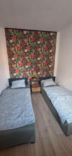 two beds in a room with a floral wall at Apartament Nova Kamienica 1 in Łagów