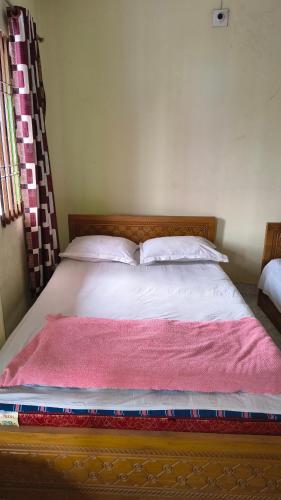 a bed with a pink blanket on top of it at Pauro Abashik Hotel in Khagrāchari