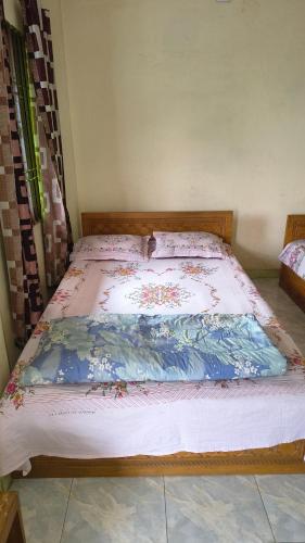 a bed in a room with a bedspread with flowers on it at Pauro Abashik Hotel in Khagrāchari