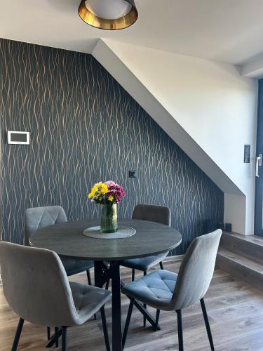 a table with chairs and a vase of flowers on it at Apartmány Pod Novou in Mikulov