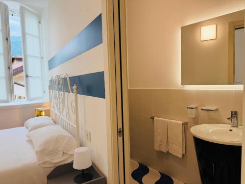 a bathroom with a bed and a sink and a mirror at Locanda Alberti in Mandello del Lario