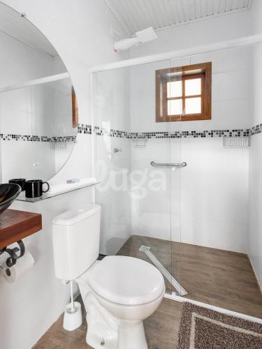 a white bathroom with a toilet and a mirror at Suite Low – Cyclists' Paradise in Gramado