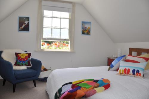ein Schlafzimmer mit einem Bett, einem Stuhl und einem Fenster in der Unterkunft Issey Manor in New Plymouth