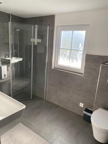 a bathroom with a shower and a toilet and a window at Hyggehus in Warnitz